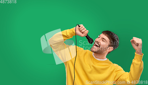 Image of man in yellow sweatshirt with microphone singing