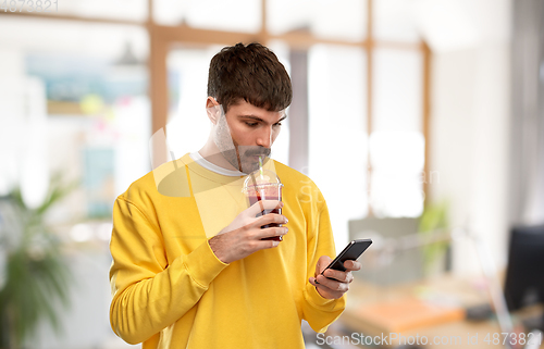 Image of man with smartphone and tomato juice at office