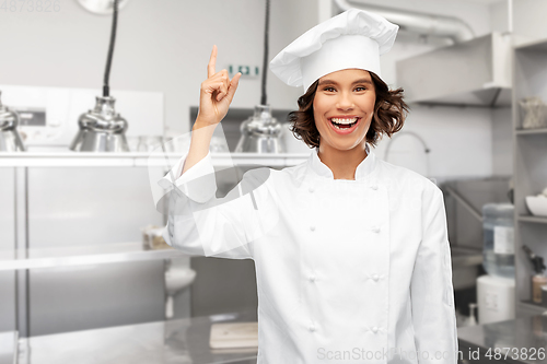 Image of female chef pointing finger up over restaurant