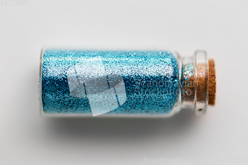 Image of blue glitters in bottle over white background