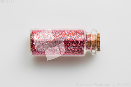 Image of red glitters in bottle over white background