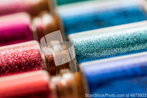 Image of set of different glitters in small glass bottles