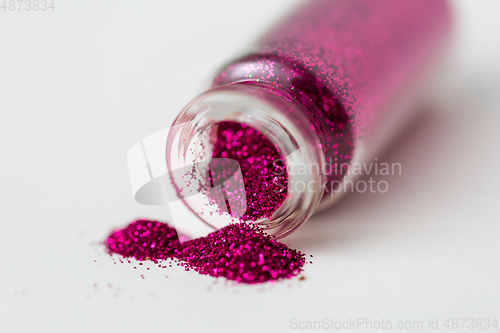 Image of pink glitters poured from small glass bottle