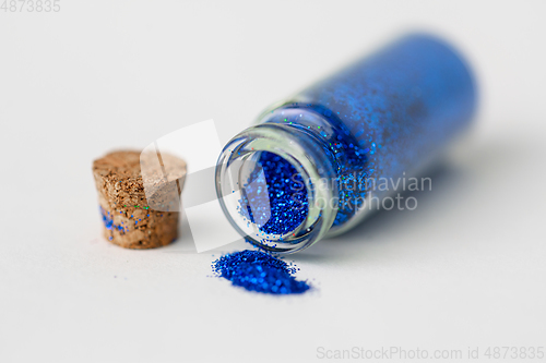 Image of blue glitters poured from small glass bottle