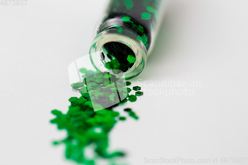 Image of green glitters poured from small glass bottle