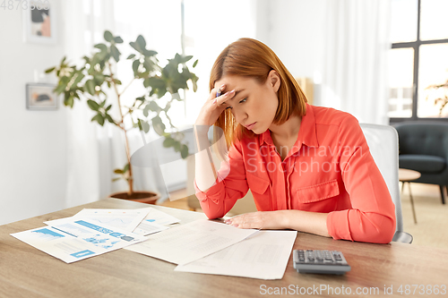 Image of woman with calculator and papers working at home