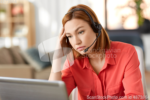 Image of sad woman with headset and laptop working at home