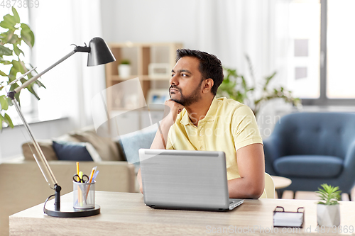 Image of indian man with laptop thinking at home office