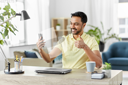 Image of indian man having video call on smartphone at home