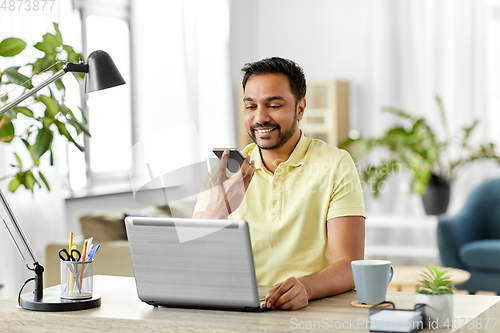 Image of man recording voice on smartphone at home office