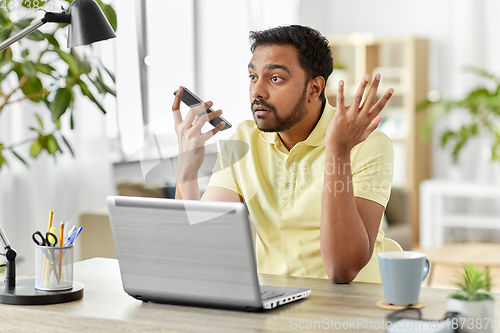 Image of man recording voice on smartphone at home office