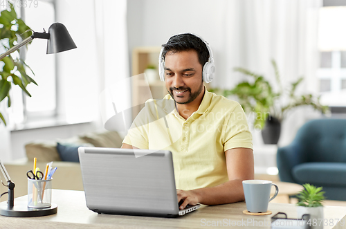 Image of man in headphones with laptop working at home