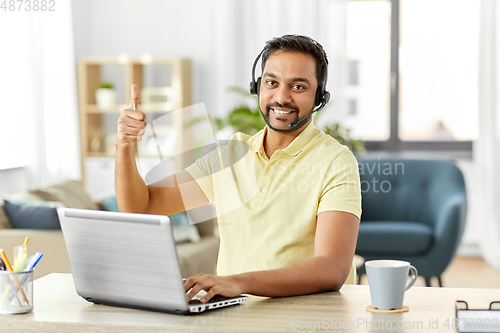 Image of indian man with headset and laptop working at home