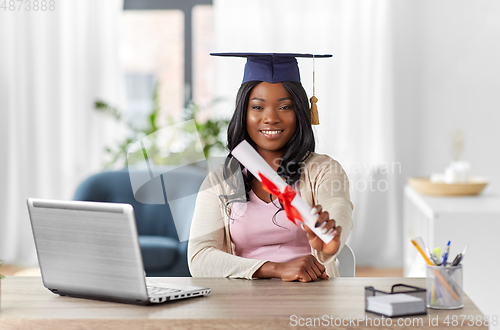 Image of graduate student with laptop and diploma at home