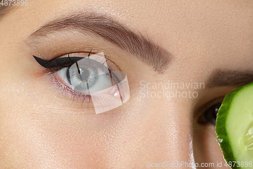 Image of Close up of beautiful young woman with cucumber slices over white background. Cosmetics and makeup, natural and eco treatment, skin care.