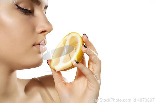 Image of Close up of beautiful young woman with lemon slices over white background. Cosmetics and makeup, natural and eco treatment, skin care.