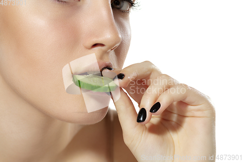 Image of Close up of beautiful young woman with cucumber slices over white background. Cosmetics and makeup, natural and eco treatment, skin care.