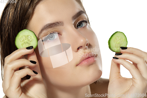 Image of Close up of beautiful young woman with cucumber slices over white background. Cosmetics and makeup, natural and eco treatment, skin care.