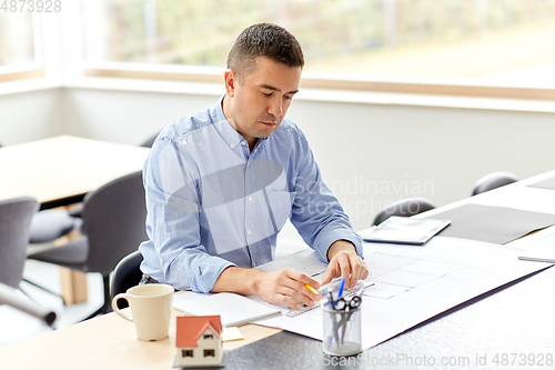 Image of architect with blueprint working at home office