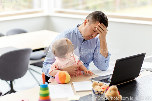 Image of father with baby working on laptop at home office