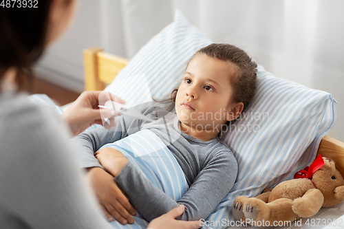 Image of mother measuring temperature of sick daughter