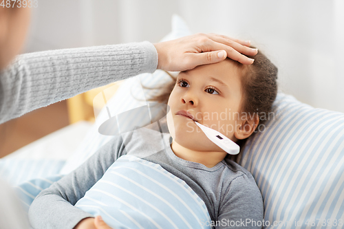 Image of mother and sick daughter measuring temperature