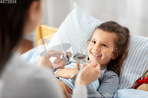 Image of mother pouring cough syrup for sick daughter