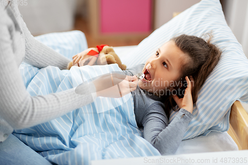 Image of mother giving cough syrup to sick daughter