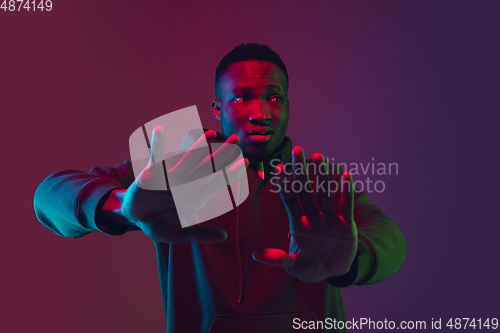 Image of African-american man\'s portrait isolated on gradient studio background in neon light