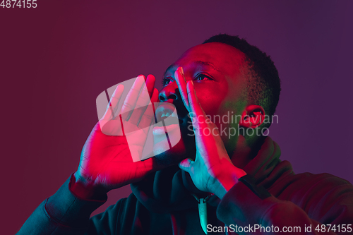 Image of African-american man\'s portrait isolated on gradient studio background in neon light