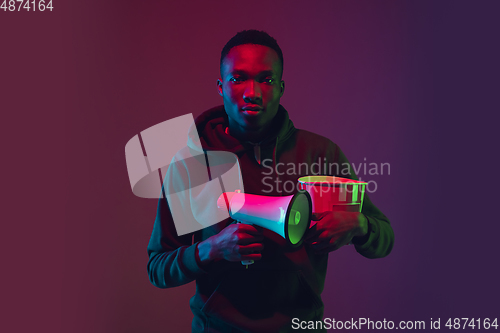 Image of African-american man\'s portrait isolated on gradient studio background in neon light
