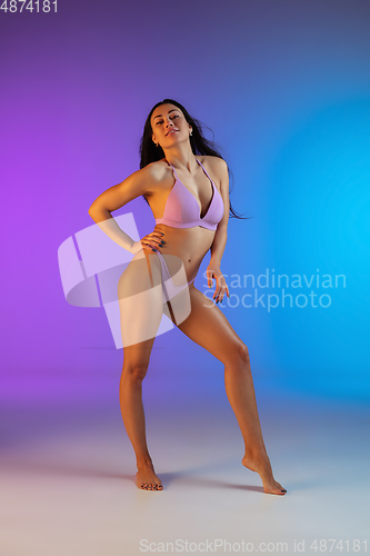 Image of Fashion portrait of young fit and sportive woman in stylish purple luxury swimwear on gradient background. Perfect body ready for summertime.