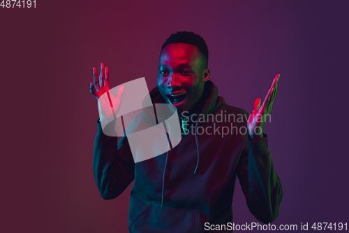 Image of African-american man\'s portrait isolated on gradient studio background in neon light