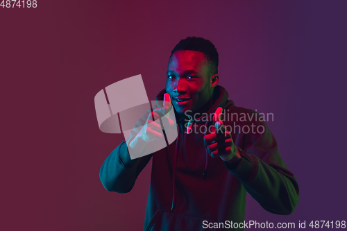 Image of African-american man\'s portrait isolated on gradient studio background in neon light