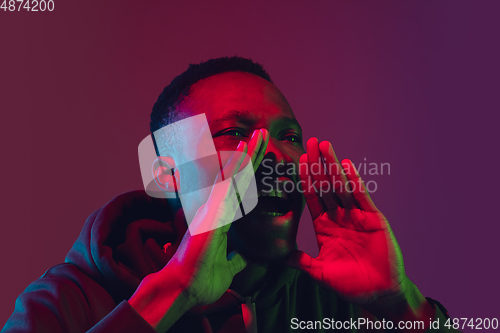 Image of African-american man\'s portrait isolated on gradient studio background in neon light