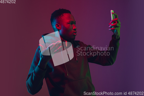 Image of African-american man\'s portrait isolated on gradient studio background in neon light