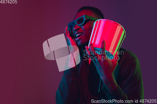 Image of African-american man\'s portrait isolated on gradient studio background in neon light