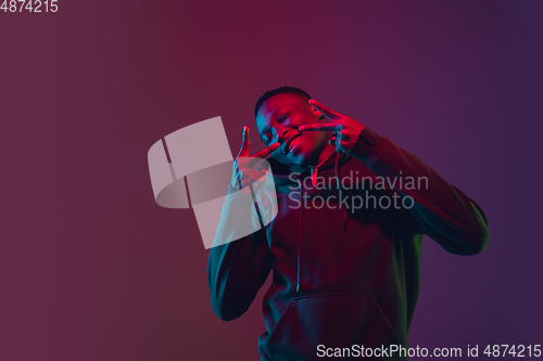 Image of African-american man\'s portrait isolated on gradient studio background in neon light