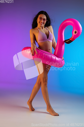 Image of Fashion portrait of young fit and sportive woman in purple luxury swimwear and stylish sunglasses on gradient background. Perfect body ready for summertime.