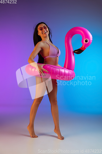 Image of Fashion portrait of young fit and sportive woman in purple luxury swimwear and stylish sunglasses on gradient background. Perfect body ready for summertime.