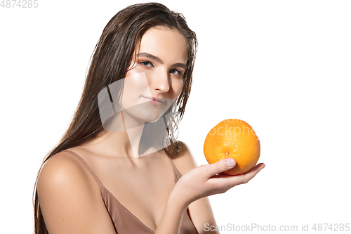 Image of Close up of beautiful female face with orange over white background. Cosmetics and makeup, natural and eco treatment, skin care.