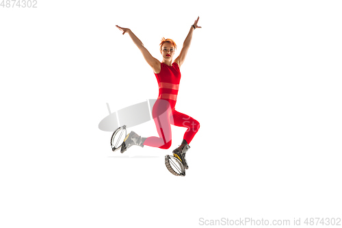 Image of Beautiful redhead woman in a red sportswear jumping in a kangoo jumps shoes isolated on white studio background.