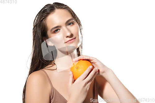 Image of Close up of beautiful female face with orange over white background. Cosmetics and makeup, natural and eco treatment, skin care.