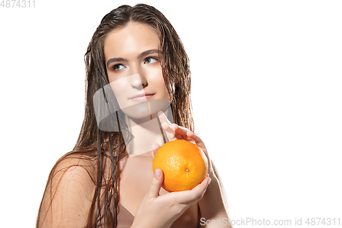 Image of Close up of beautiful female face with orange over white background. Cosmetics and makeup, natural and eco treatment, skin care.