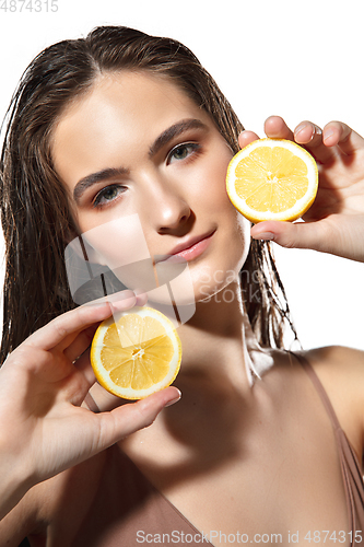 Image of Citrus. Close up of beautiful female face with lemon slices over white background. Cosmetics and makeup, natural and eco treatment, skin care.