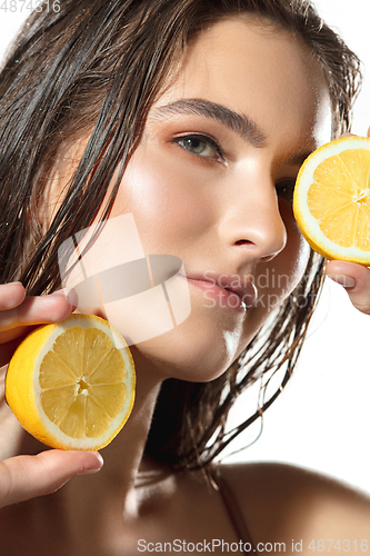 Image of Citrus. Close up of beautiful female face with lemon slices over white background. Cosmetics and makeup, natural and eco treatment, skin care.