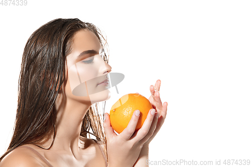 Image of Close up of beautiful female face with orange over white background. Cosmetics and makeup, natural and eco treatment, skin care.