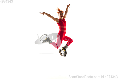 Image of Beautiful redhead woman in a red sportswear jumping in a kangoo jumps shoes isolated on white studio background.