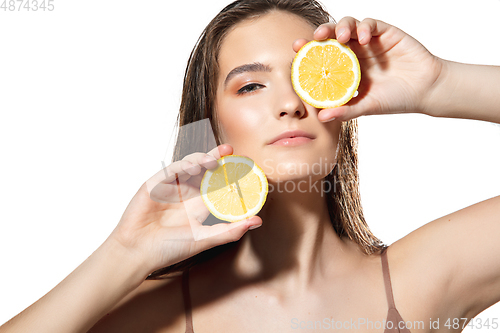 Image of Citrus. Close up of beautiful female face with lemon slices over white background. Cosmetics and makeup, natural and eco treatment, skin care.