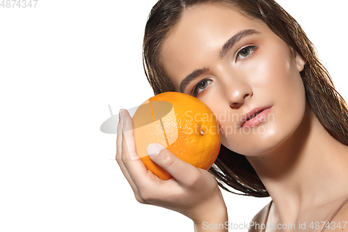 Image of Close up of beautiful female face with orange over white background. Cosmetics and makeup, natural and eco treatment, skin care.
